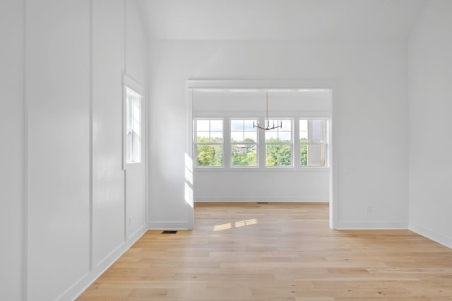 unfurnished room with an inviting chandelier and light wood-type flooring