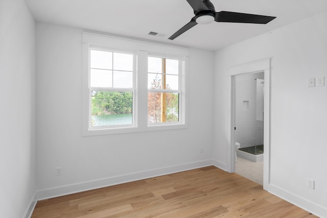 unfurnished bedroom featuring ceiling fan, ensuite bathroom, and light wood-type flooring