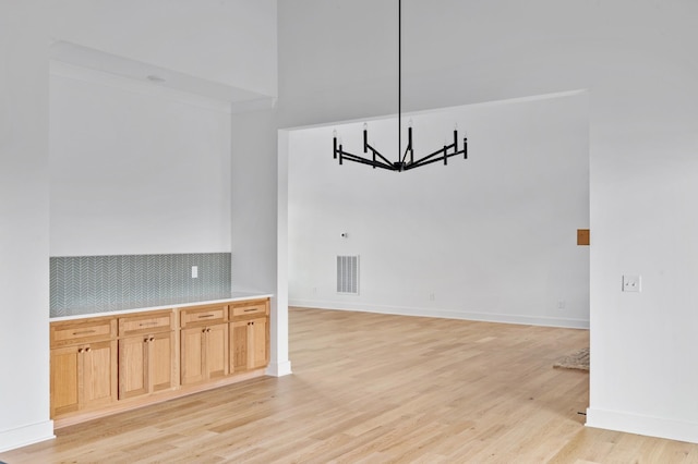 unfurnished dining area featuring light hardwood / wood-style floors and a chandelier