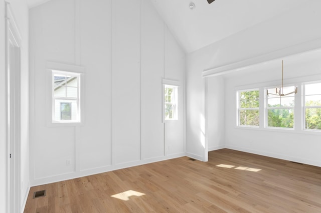 empty room with high vaulted ceiling and light hardwood / wood-style flooring