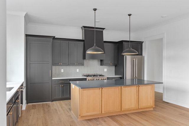 kitchen with light wood-type flooring, high quality fridge, wall chimney exhaust hood, and a kitchen island