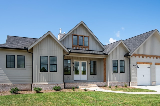 view of front facade featuring french doors, a garage, covered porch, and a front lawn