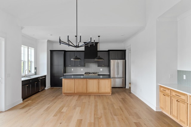 kitchen with stainless steel appliances, a center island, light brown cabinets, and light hardwood / wood-style flooring