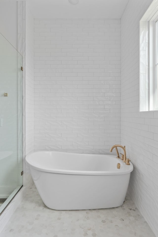 bathroom with tile walls and independent shower and bath