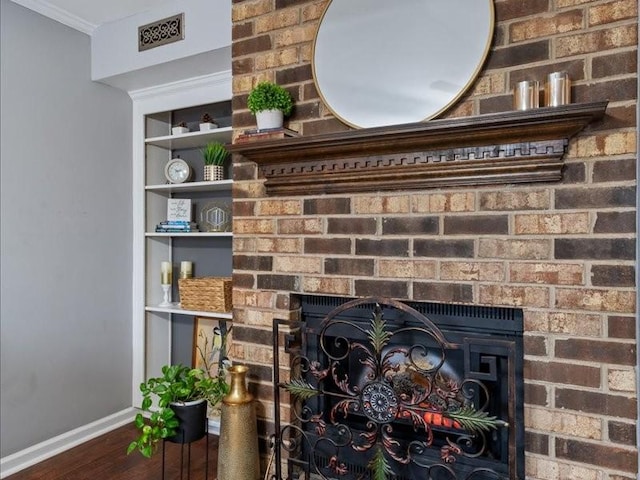 interior details with ornamental molding, hardwood / wood-style floors, and a brick fireplace