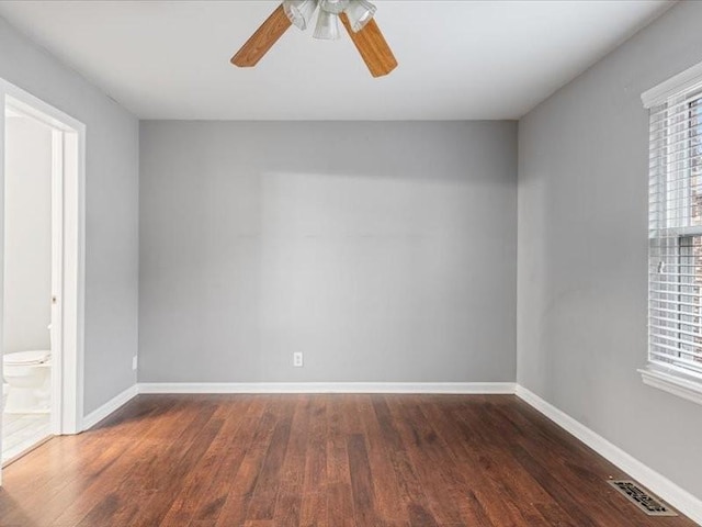 empty room with ceiling fan and dark hardwood / wood-style flooring