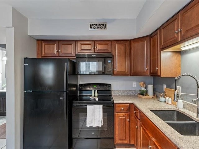 kitchen with light stone counters, sink, and black appliances