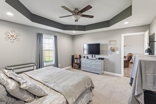 carpeted bedroom with ceiling fan and a tray ceiling