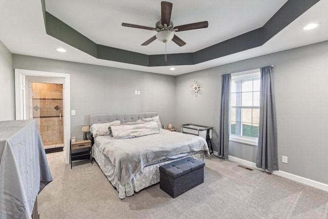 bedroom featuring ceiling fan, light colored carpet, and a tray ceiling