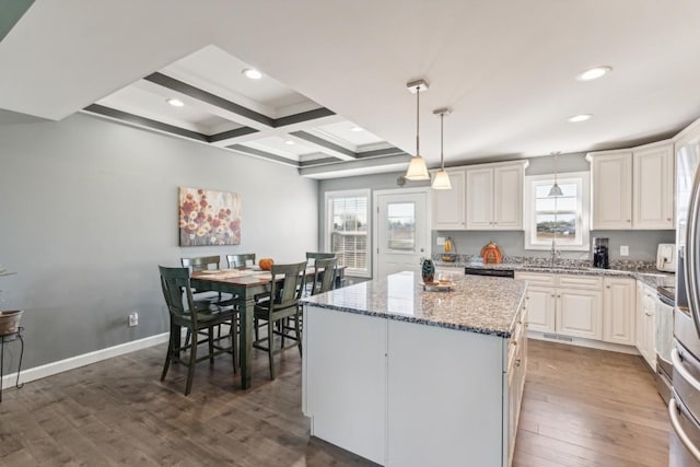 kitchen featuring white cabinetry, a center island, pendant lighting, and light stone counters