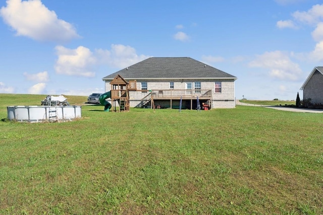 back of property with a pool side deck, a playground, and a lawn