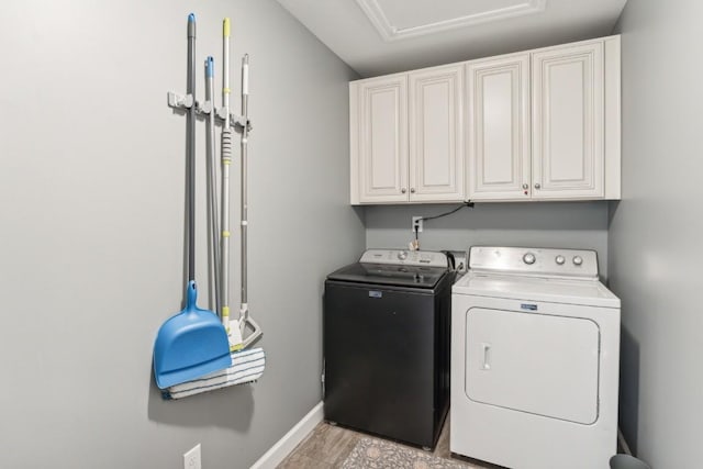 clothes washing area featuring cabinets and washing machine and clothes dryer