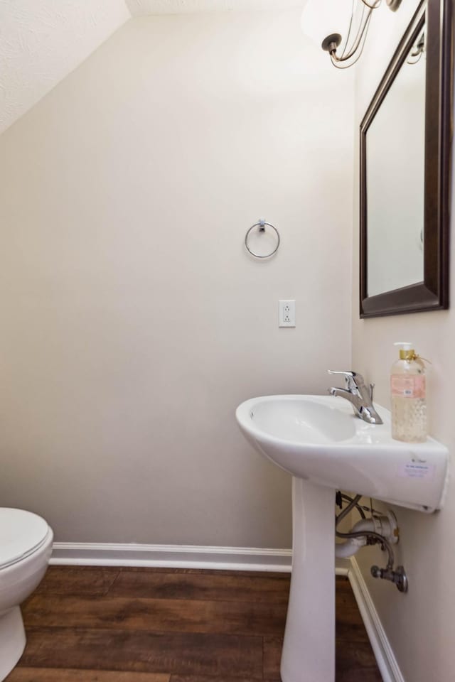 bathroom with wood-type flooring, toilet, and vaulted ceiling