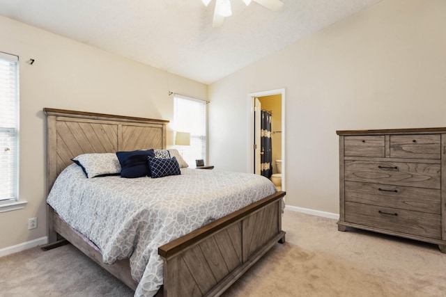 carpeted bedroom featuring multiple windows, vaulted ceiling, connected bathroom, and ceiling fan