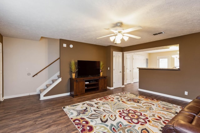 living room featuring ceiling fan, dark hardwood / wood-style floors, and a textured ceiling