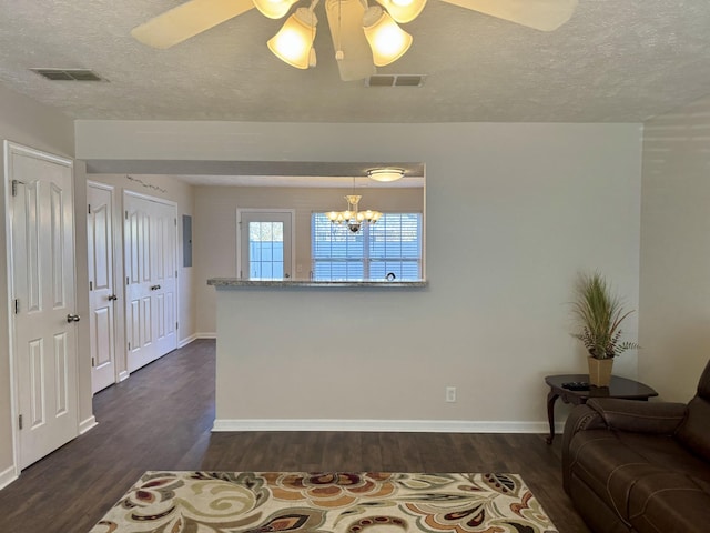 unfurnished living room with dark wood-style floors, baseboards, visible vents, and a textured ceiling