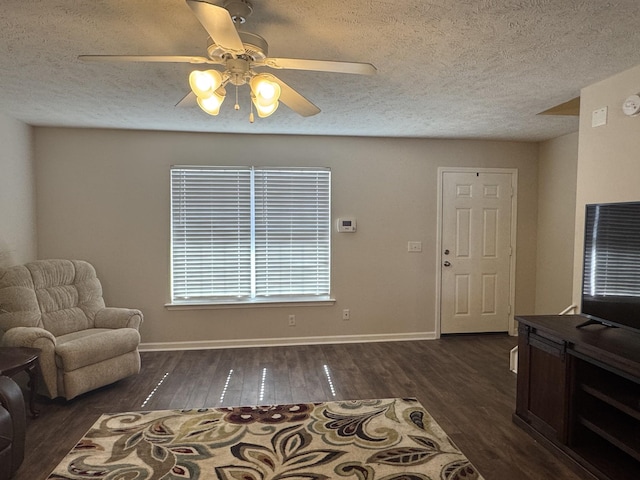 living area featuring dark wood-style flooring, ceiling fan, a textured ceiling, and baseboards