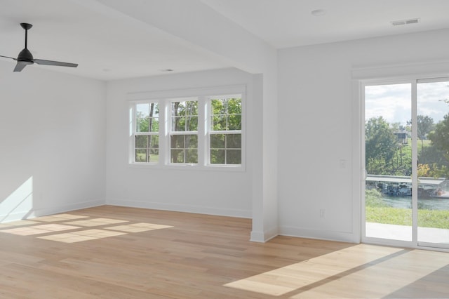 empty room with ceiling fan, light hardwood / wood-style floors, and a healthy amount of sunlight