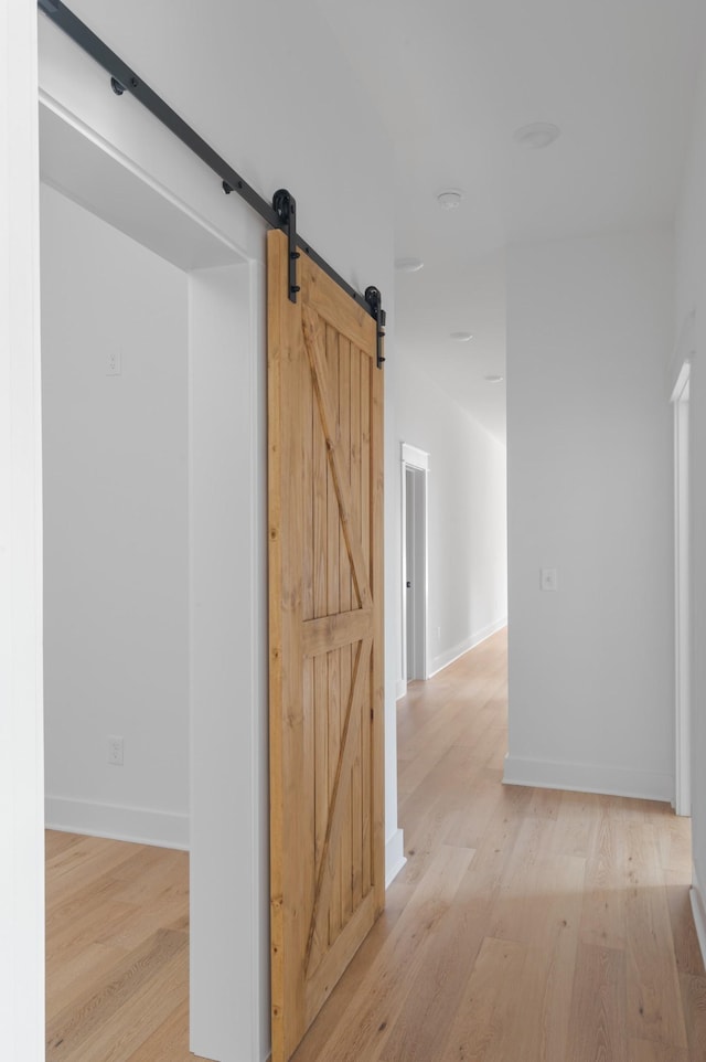 hallway featuring a barn door and light hardwood / wood-style floors