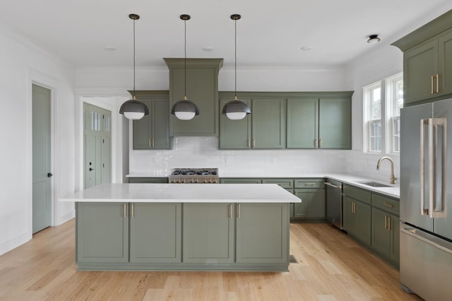 kitchen featuring sink, appliances with stainless steel finishes, hanging light fixtures, a center island, and green cabinetry