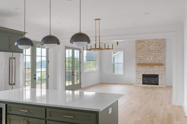 kitchen with a kitchen island, green cabinets, hanging light fixtures, and light wood-type flooring