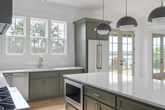 kitchen with pendant lighting, sink, light hardwood / wood-style flooring, appliances with stainless steel finishes, and french doors