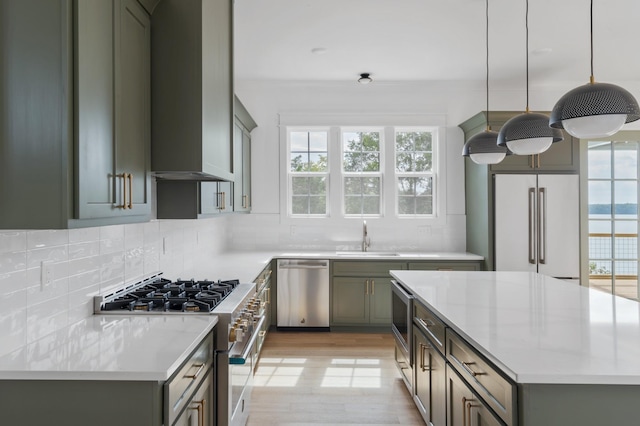 kitchen with sink, backsplash, premium appliances, hanging light fixtures, and light stone counters