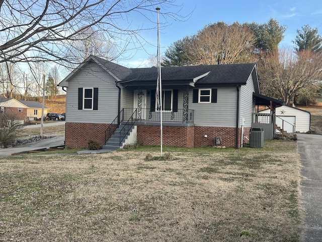 view of front facade featuring a porch, central AC unit, a garage, an outbuilding, and a front lawn