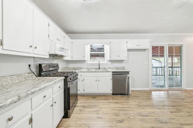 kitchen with sink, light hardwood / wood-style flooring, white cabinets, and appliances with stainless steel finishes