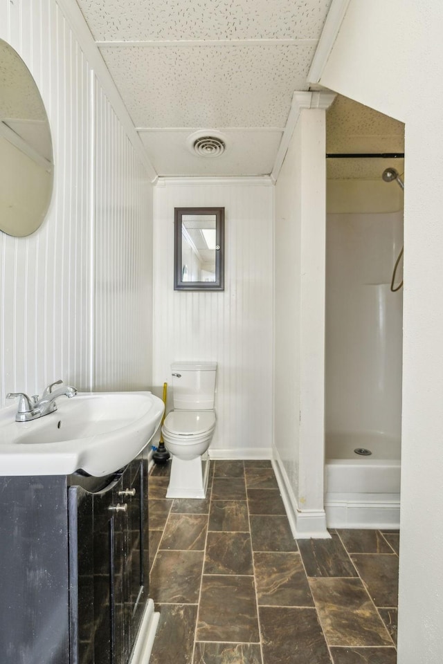 bathroom featuring vanity, toilet, a drop ceiling, and a shower