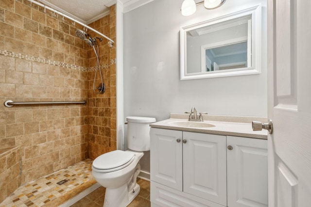 bathroom featuring tile patterned floors, vanity, toilet, and a tile shower