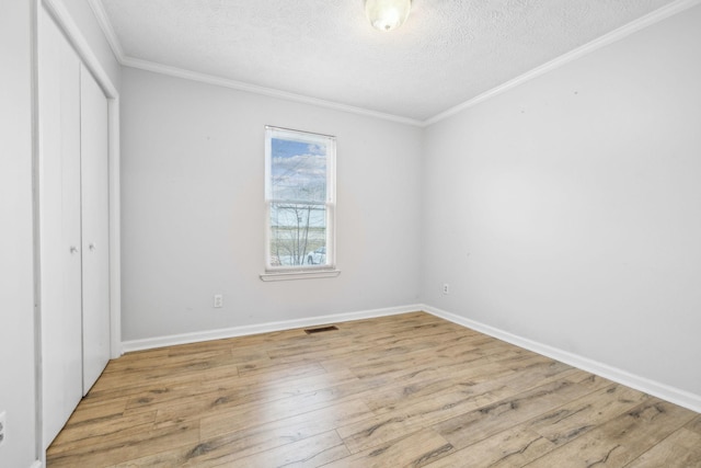 unfurnished bedroom featuring crown molding, light hardwood / wood-style floors, a closet, and a textured ceiling