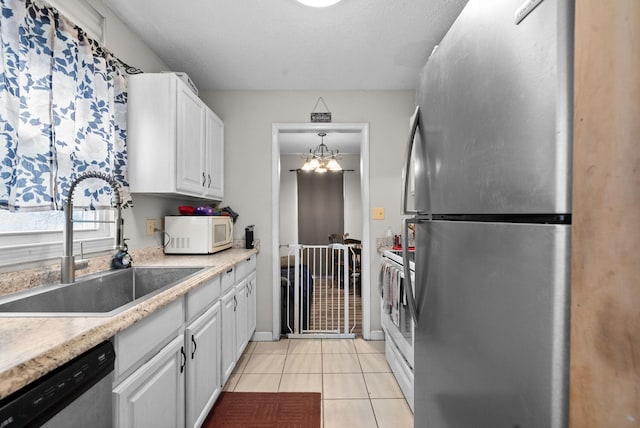 kitchen featuring sink, white cabinetry, an inviting chandelier, light tile patterned floors, and appliances with stainless steel finishes