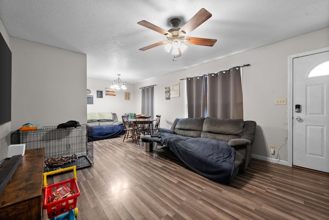 living room featuring ceiling fan with notable chandelier, dark hardwood / wood-style floors, and a textured ceiling