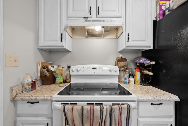 kitchen featuring black refrigerator, white cabinetry, light stone counters, and electric range