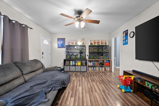 living room featuring a textured ceiling, wood-type flooring, and ceiling fan