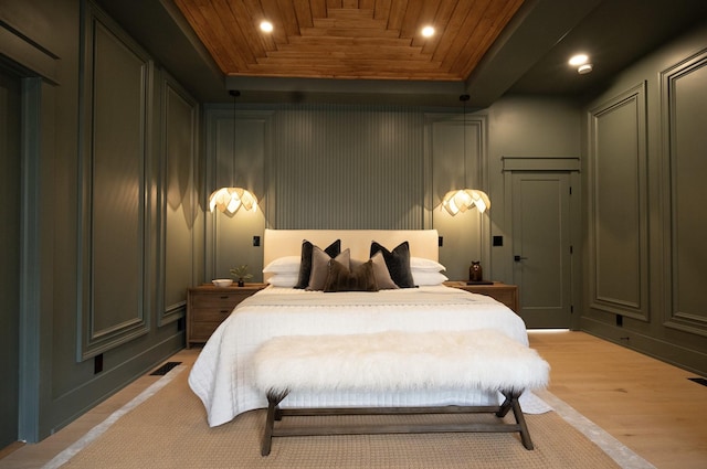 bedroom with wooden ceiling, light hardwood / wood-style floors, and a tray ceiling