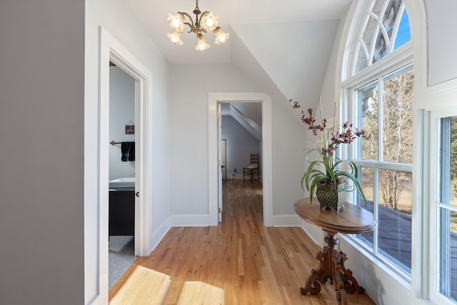 hall featuring vaulted ceiling, light hardwood / wood-style floors, and a chandelier