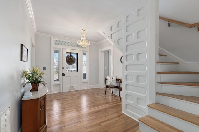 entryway featuring ornamental molding, a chandelier, and light wood-type flooring