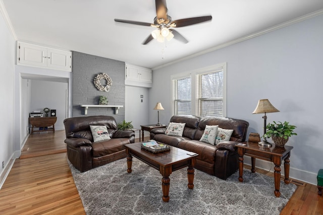 living room featuring a brick fireplace, crown molding, wood-type flooring, and ceiling fan