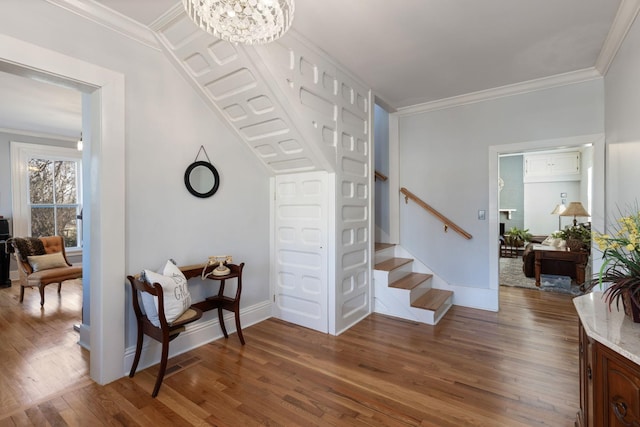 foyer with crown molding, hardwood / wood-style floors, and a notable chandelier