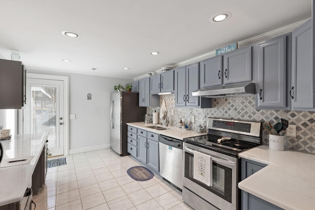 kitchen with light tile patterned flooring, sink, ornamental molding, appliances with stainless steel finishes, and backsplash