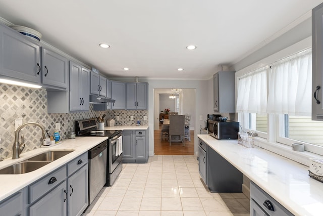 kitchen featuring appliances with stainless steel finishes, tasteful backsplash, sink, gray cabinetry, and an inviting chandelier