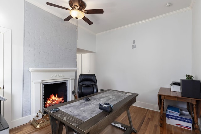 office with hardwood / wood-style flooring, ceiling fan, crown molding, and a brick fireplace