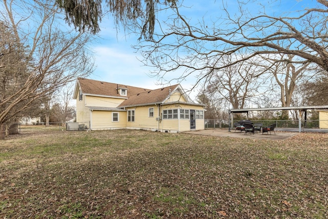 rear view of house featuring a yard, a sunroom, and a patio area