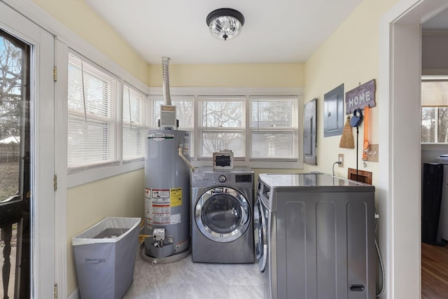 clothes washing area with a wealth of natural light, gas water heater, electric panel, and independent washer and dryer