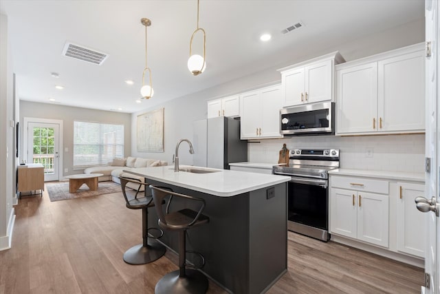 kitchen featuring white cabinetry, sink, decorative light fixtures, and stainless steel appliances