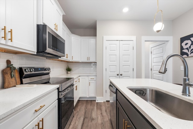 kitchen with stainless steel appliances, white cabinetry, sink, and pendant lighting