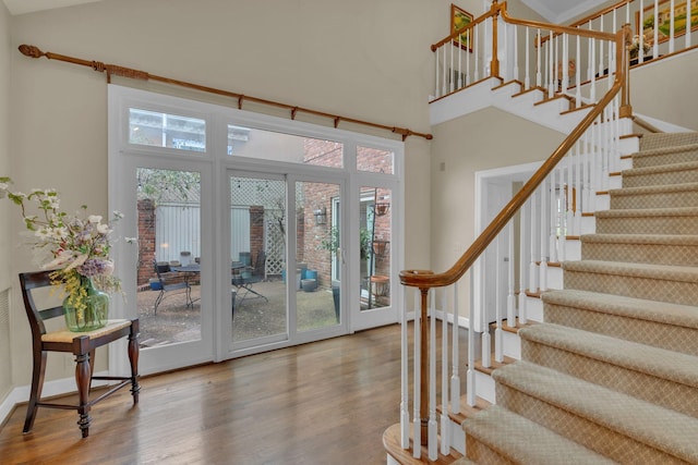 interior space featuring stairs, wood finished floors, a towering ceiling, and baseboards