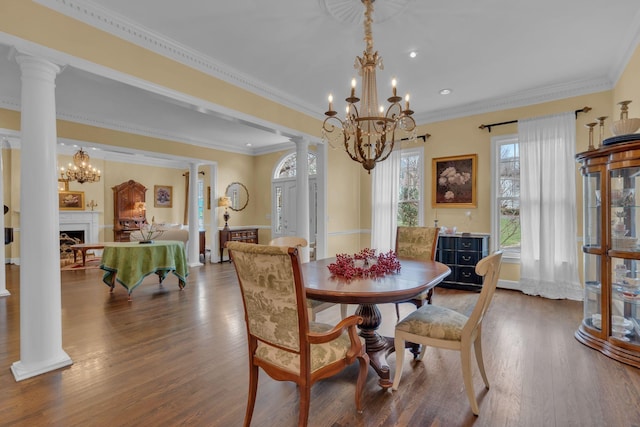 dining area with ornate columns, a fireplace, a chandelier, and wood finished floors